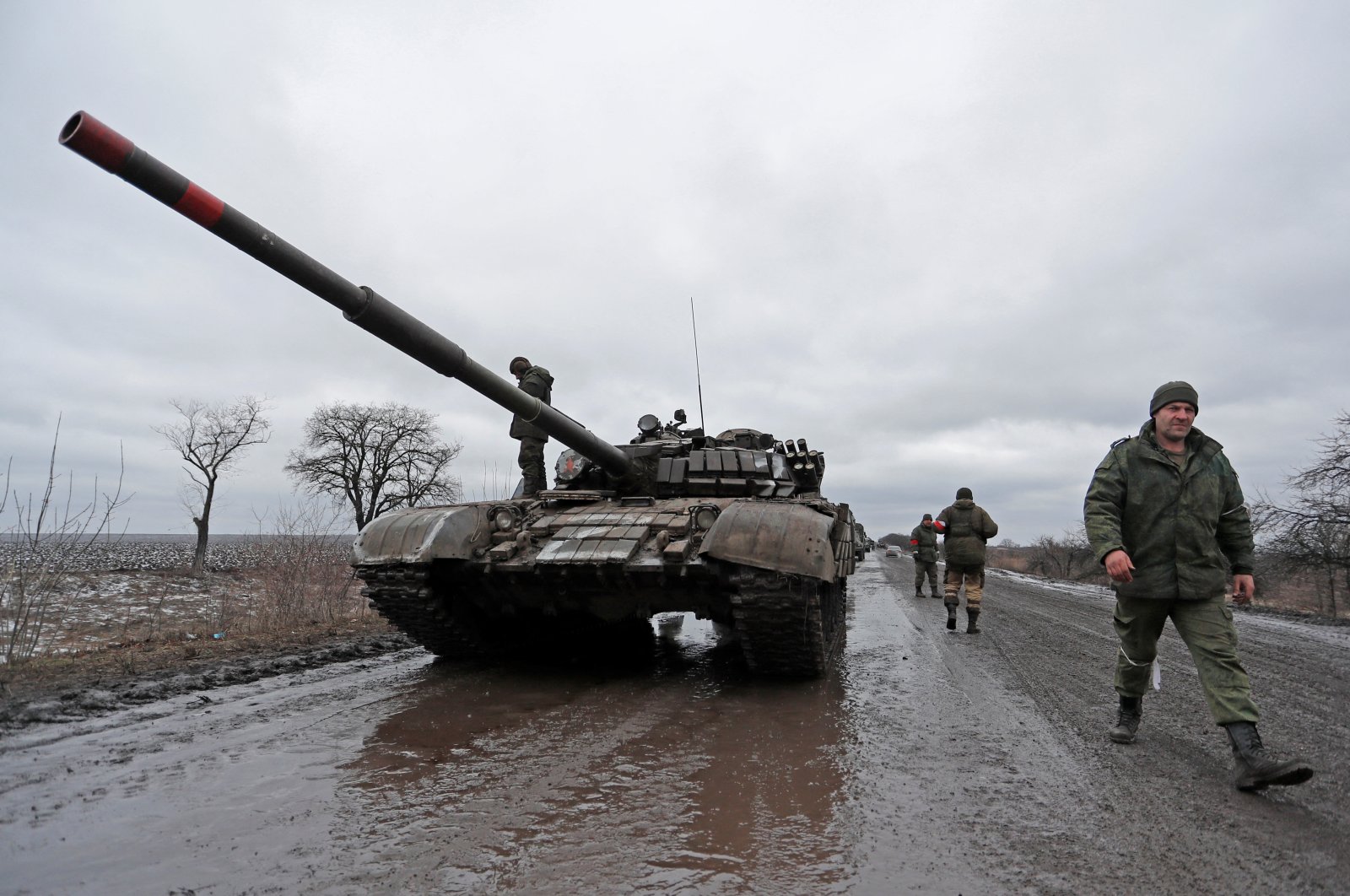 Members of a pro-Russian militia walk next to a military convoy of the armed forces of the separatist self-proclaimed Luhansk People&#039;s Republic (LNR), on a road in the Luhansk region, Ukraine, Feb. 27, 2022. (Reuters Photo)