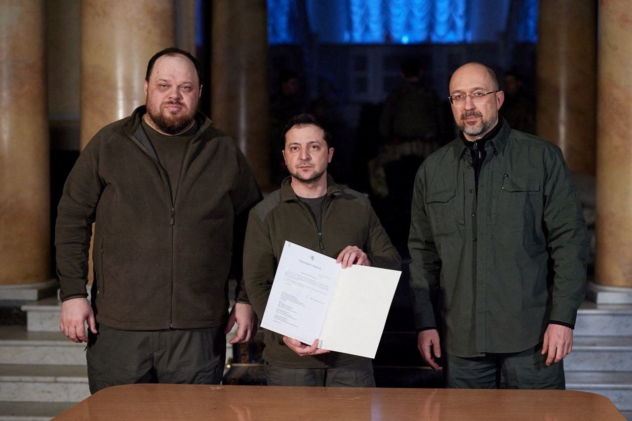 Ukrainian President Volodymyr Zelenskyy (C) poses with Prime Minister Denys Shmygal (R) and Parliament Speaker Ruslan Stefanchuk after signing an official request for Ukraine to join the European Union in Kyiv, Ukraine, Feb. 28, 2022. (Ukrainian Presidential Press Service via Reuters)