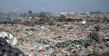 A waste picker sits by a pile of empty bottles at the Dandora garbage dump where people make a living scavenging for reusables and recyclables that can be resold in Nairobi, Kenya, Feb. 26, 2022. (AFP Photo)