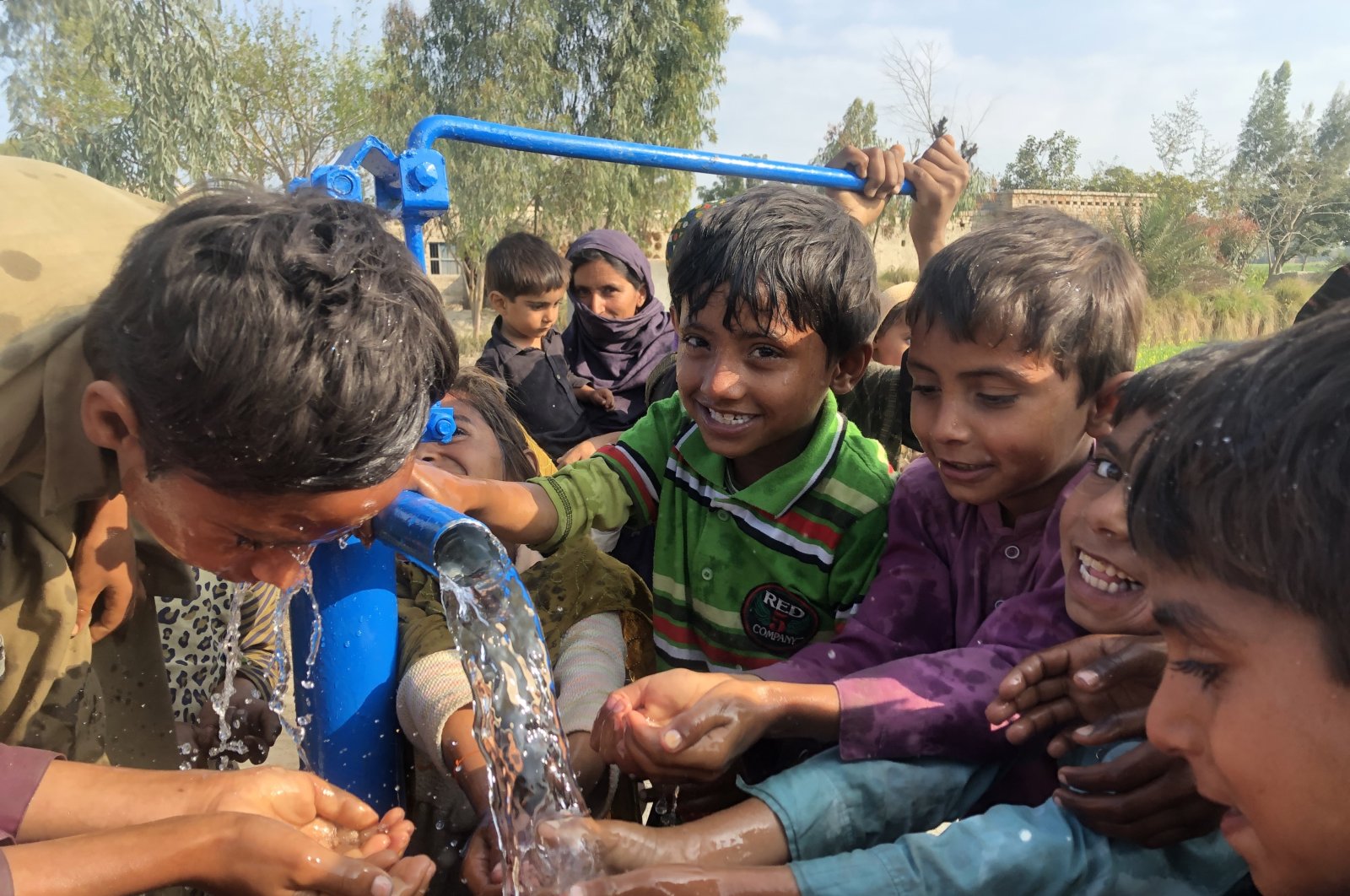 Children drink water from a well, in Muzaffargarh, Pakistan, Feb. 27, 2022. (AA PHOTO)