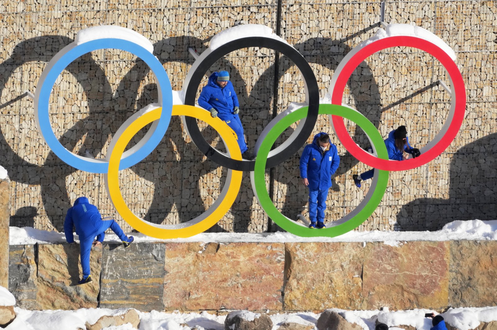 Ukraine team members climb on the Olympic Rings to pose for a photo at the 2022 Winter Games Village, Beijing, China, Feb. 14, 2022. (AP Photo)