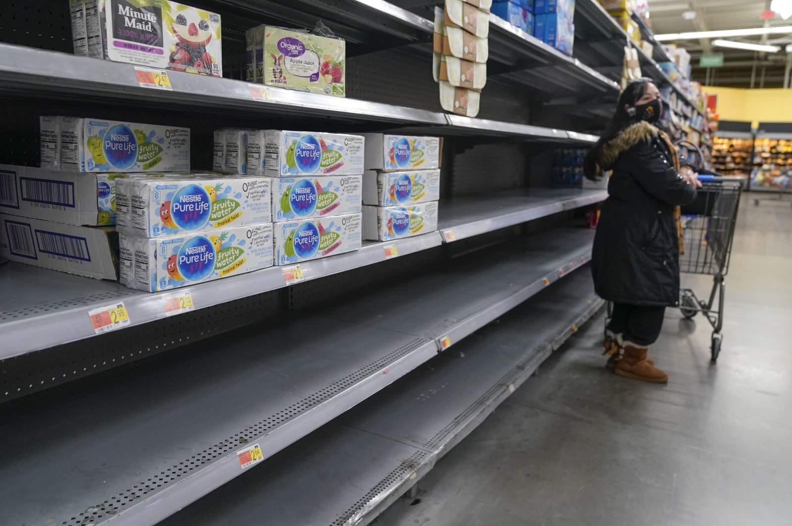  A woman looks over shelves, some of which are empty, at a Walmart store in Teterboro, N.J., U.S., Jan. 12, 2022. (AP Photo)