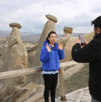 Chen Xuan stands in front of "fairy chimneys" as her fiance Burhan Güney shoots a video, in Nevşehir, central Turkey, March 2, 2022. (AA PHOTO)