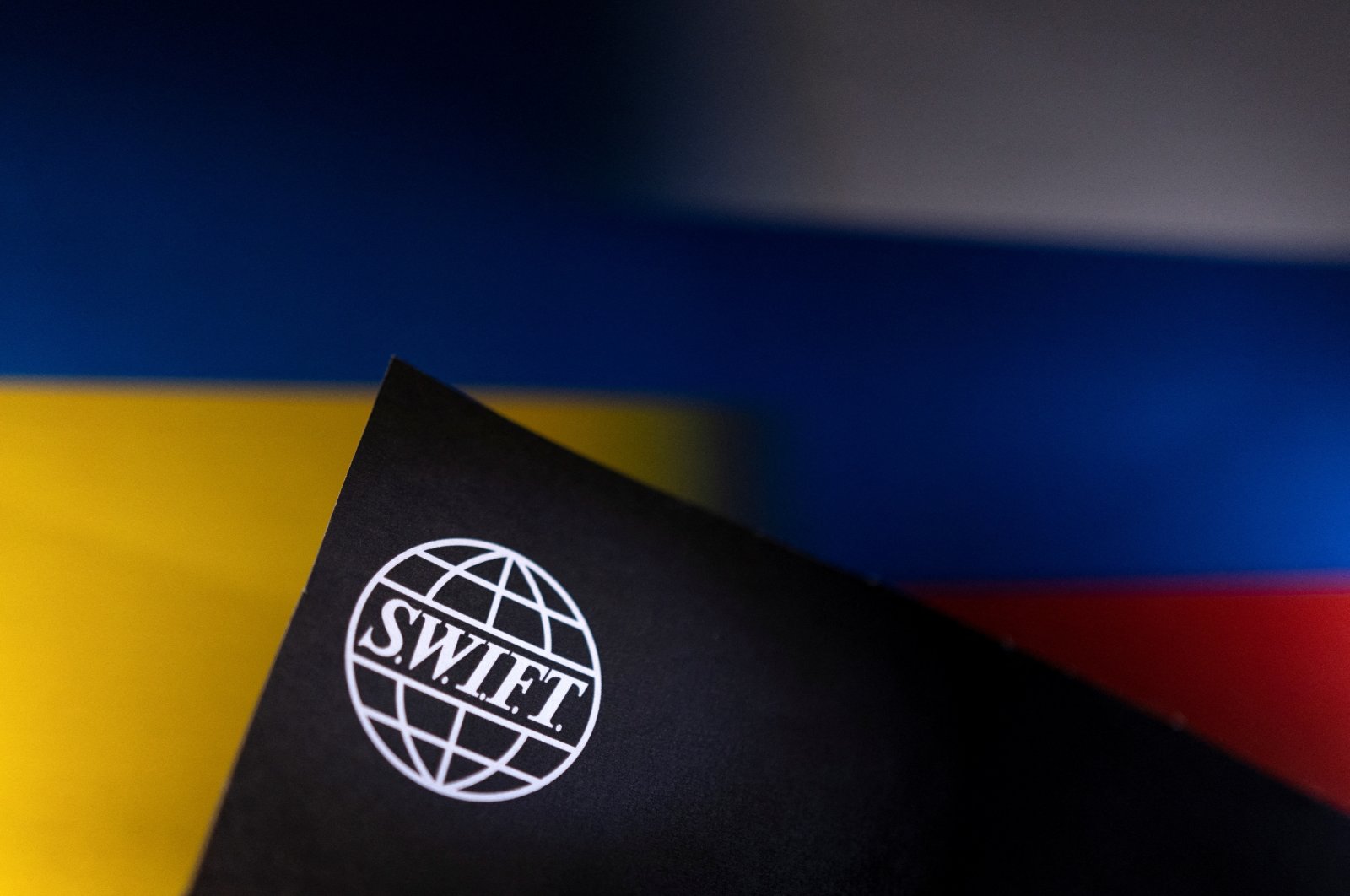 A SWIFT logo is placed on Ukrainian&#039;s and Russian&#039;s flag colors in this illustration photo, Bosnia-Herzegovina, Feb. 25, 2022. (Reuters Photo)
