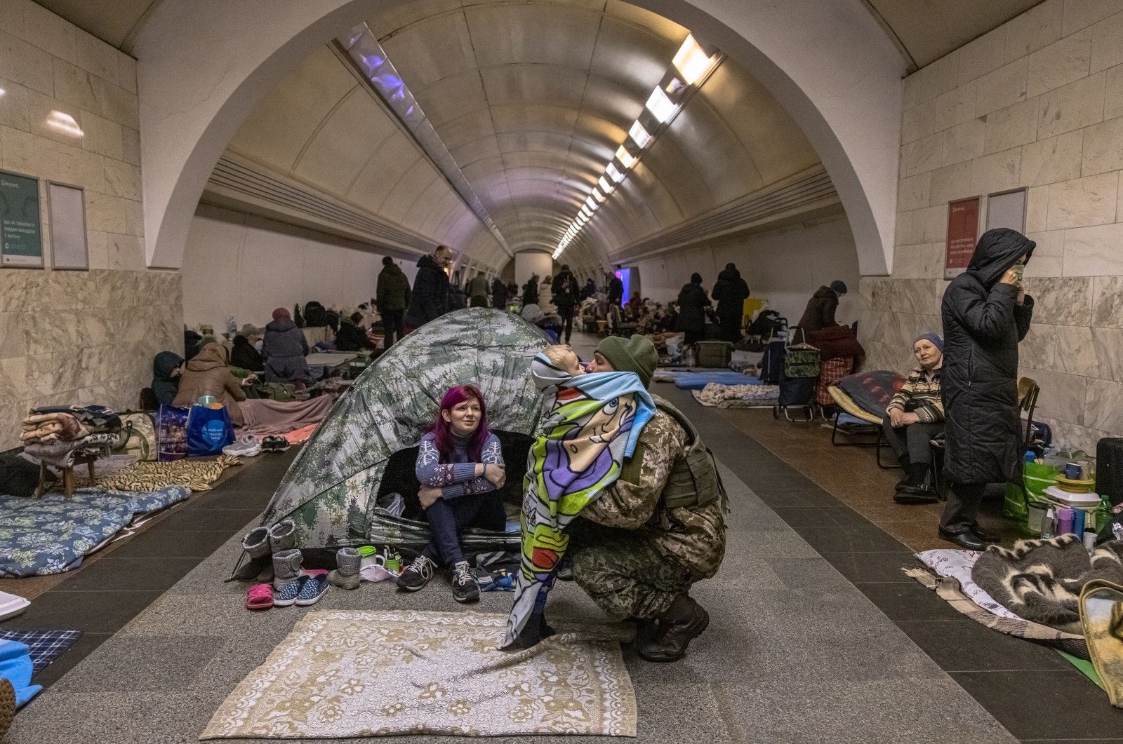 A Ukrainian military member who came inside Dorohozhychi subway station which is used as a bomb shelter, hugs his son staying there, in Kyiv, Ukraine, 02 March 2022. (EPA Photo)