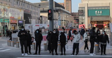 People wearing face masks wait to cross a street in Beijing, China, Feb, 23, 2022. (EPA Photo)