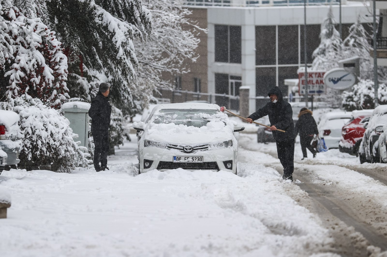 People clear the snow off a car, in the capital Ankara, Turkey, March 3, 2022. (AA PHOTO)