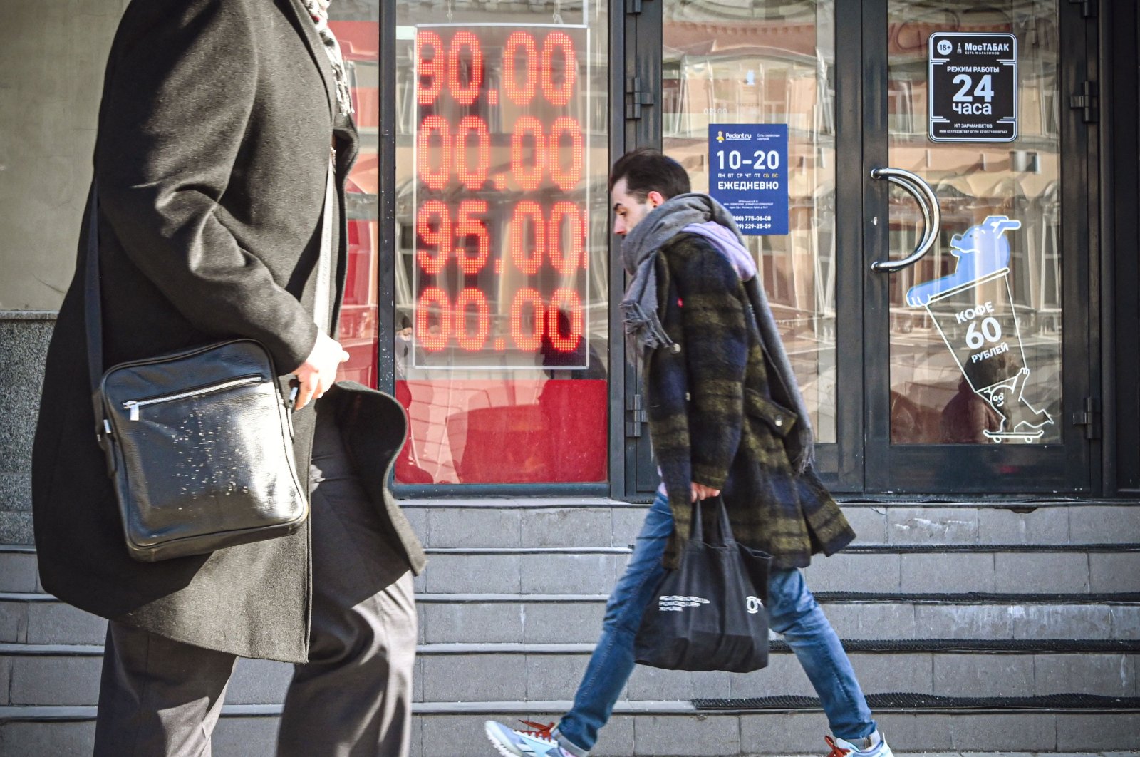 People walk past a currency exchange office, with zeros on the scoreboard since there are no three-digit sections on it to display the current exchange rate, in central Moscow, Russia, Feb. 28, 2022. (AFP Photo)