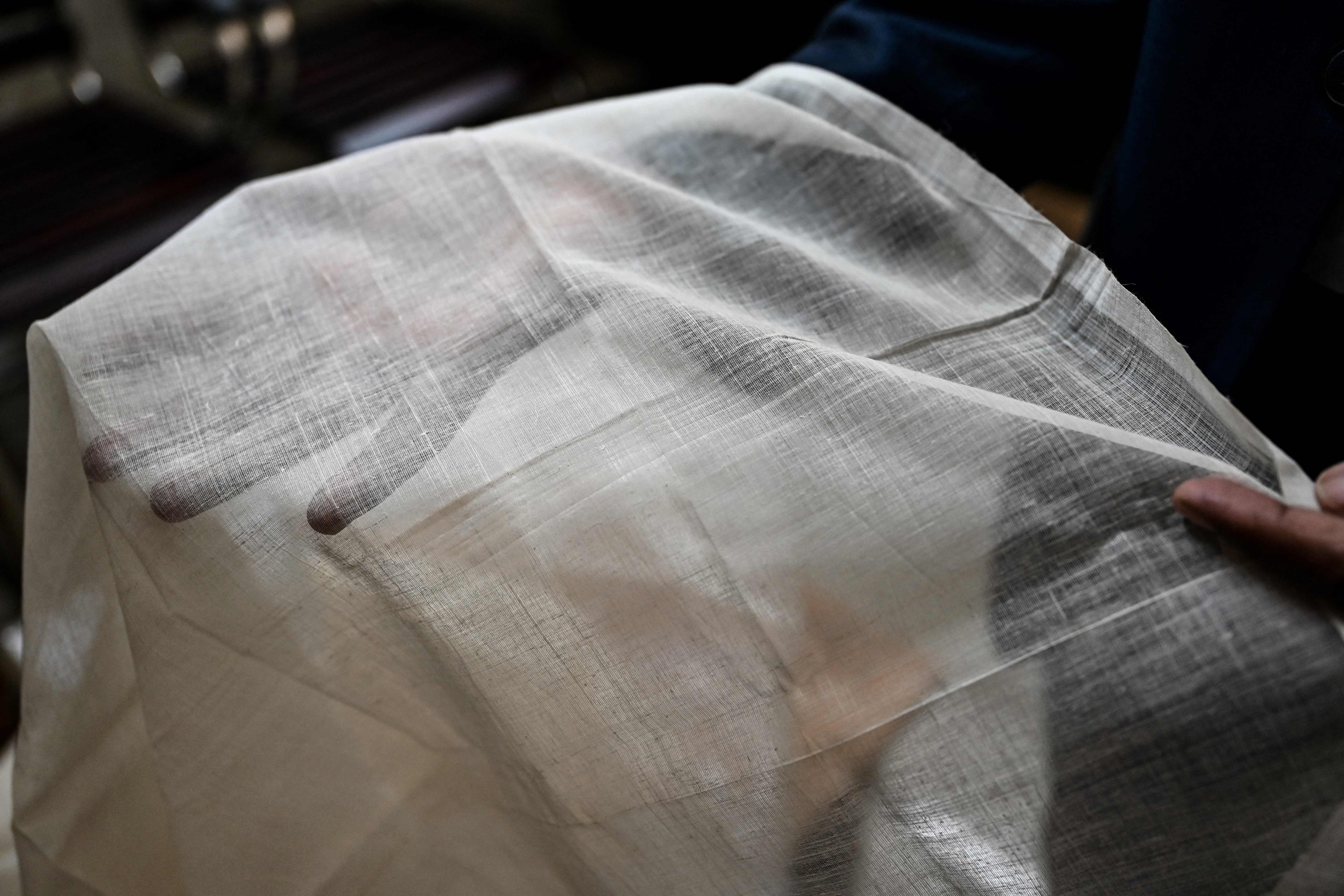 Ayub Ali, seorang pejabat senior pemerintah membantu menggembalakan proyek kebangkitan kain muslin Dhaka, memamerkan selembar kain muslin di kantornya di Dhaka, Bangladesh, 9 Januari 2022. (AFP)