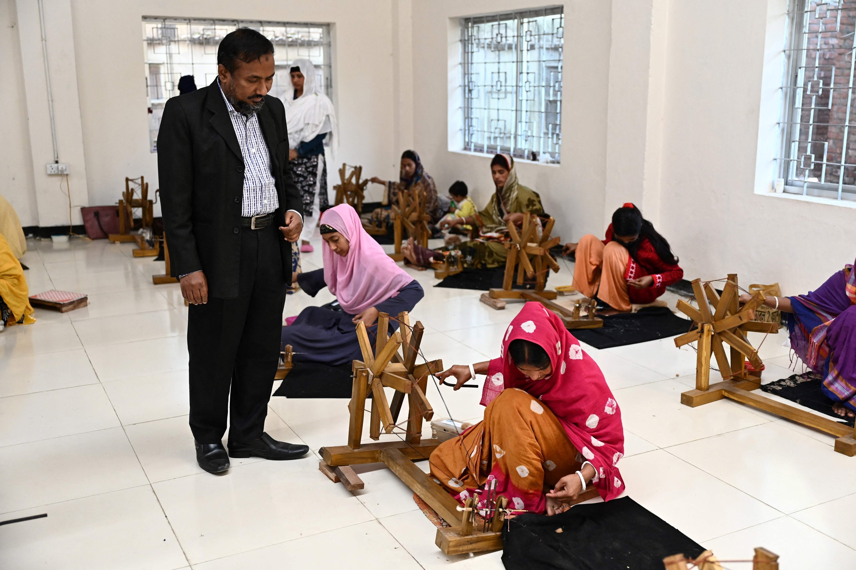 Ayub Ali, seorang pejabat senior pemerintah membantu menggembalakan proyek kebangkitan kain muslin Dhaka, melihat para pekerja memintal benang dari kapas untuk membuat pakaian kain muslin tradisional di fasilitas Proyek Muslin Dhakai di Narayanganj, Dhaka, Bangladesh, 9 Januari 2022. (AFP)