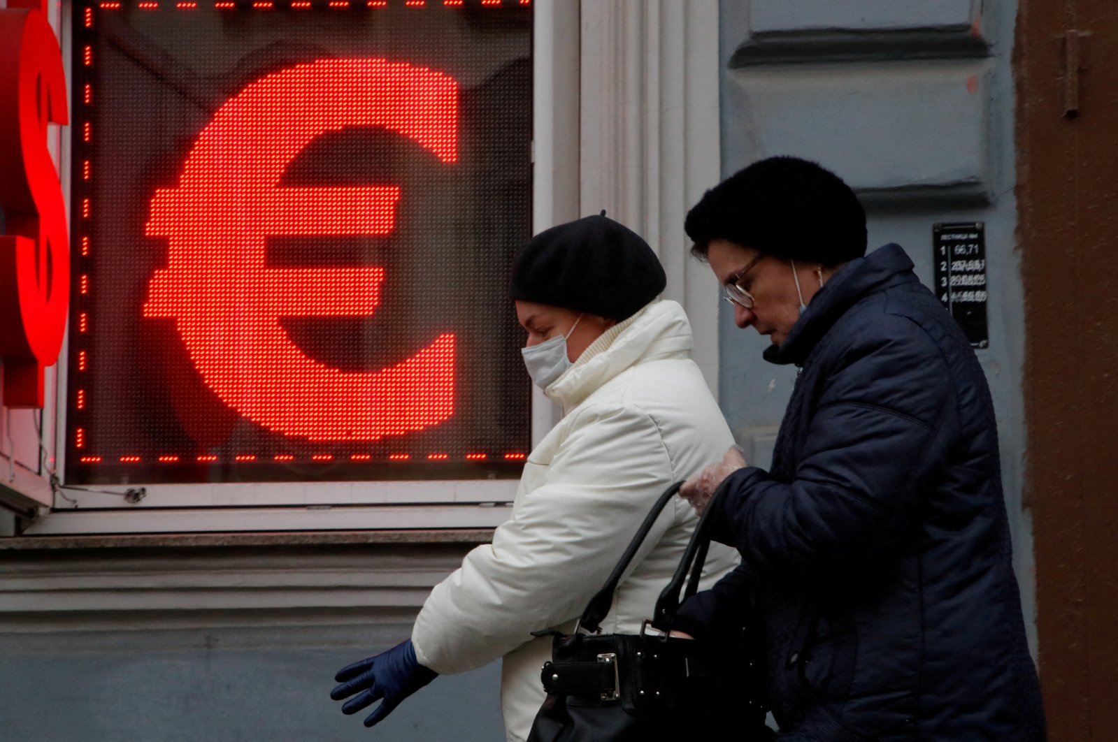 Women walk past a board showing the U.S. dollar and euro signs in a street in Saint Petersburg, Russia, Feb. 25, 2022. (Reuters Photo)