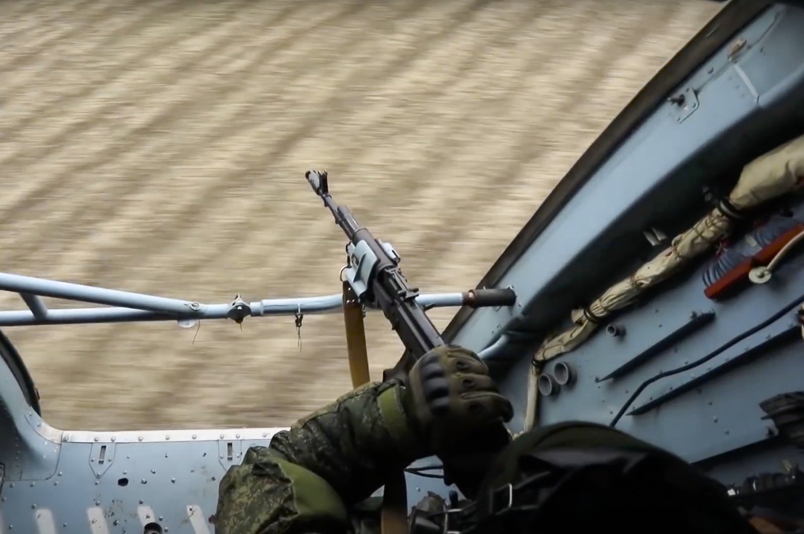 In this photo taken from video released by the Russian Defense Ministry Press Service, a Russian soldier points a gun from a Russian military helicopter as it flies over an undisclosed location in Ukraine, March 3, 2022. (AP Photo)