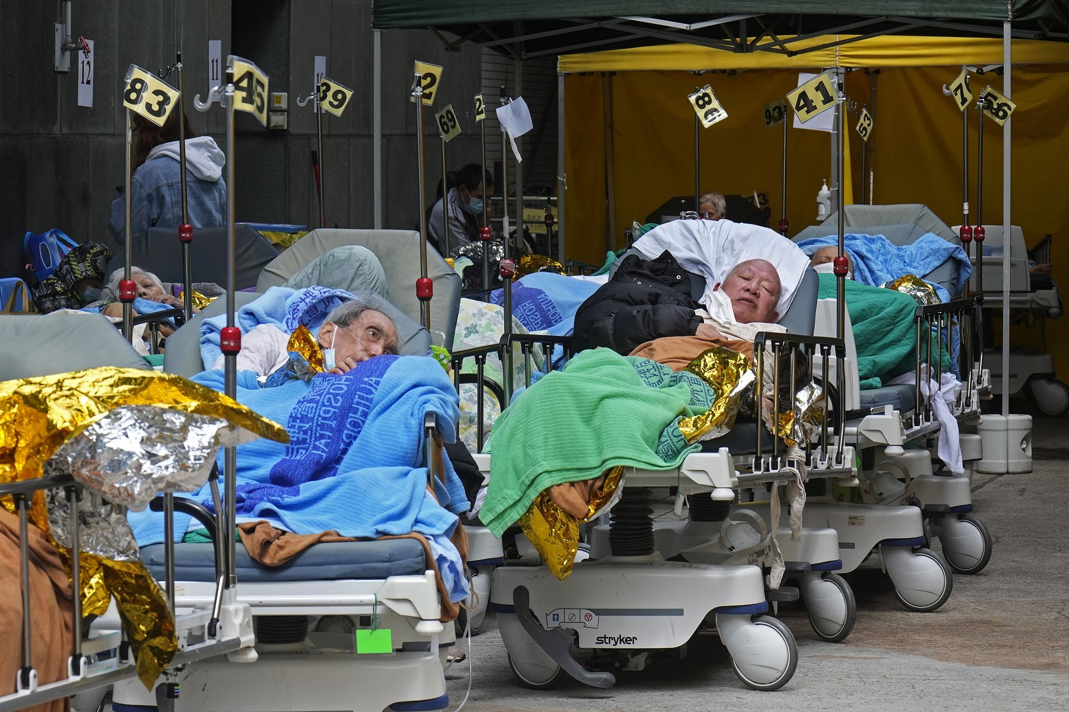 Pasien berbaring di ranjang rumah sakit menunggu di ruang tunggu sementara di luar Caritas Medical Center di Hong Kong, 16 Februari 2022. (AP Photo)