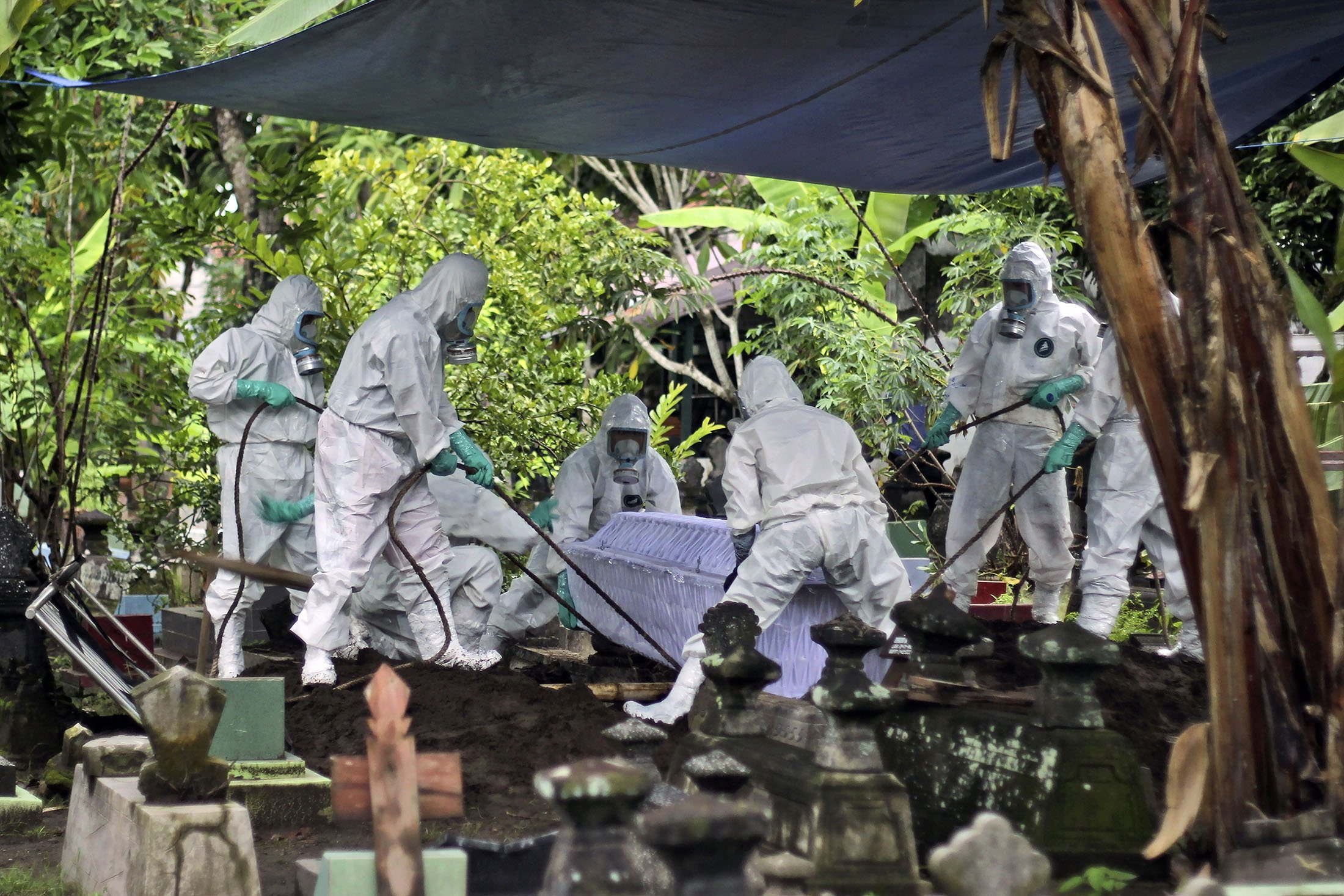 Pekerja dengan alat pelindung mengubur korban virus corona saat pemakaman di pemakaman di Yogyakarta, Indonesia, 17 Februari 2022. (AP Photo)