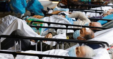 Patients wearing face masks rest at a makeshift treatment area outside a hospital, following the coronavirus outbreak in Hong Kong, China, March 2, 2022. (Reuters Photo)