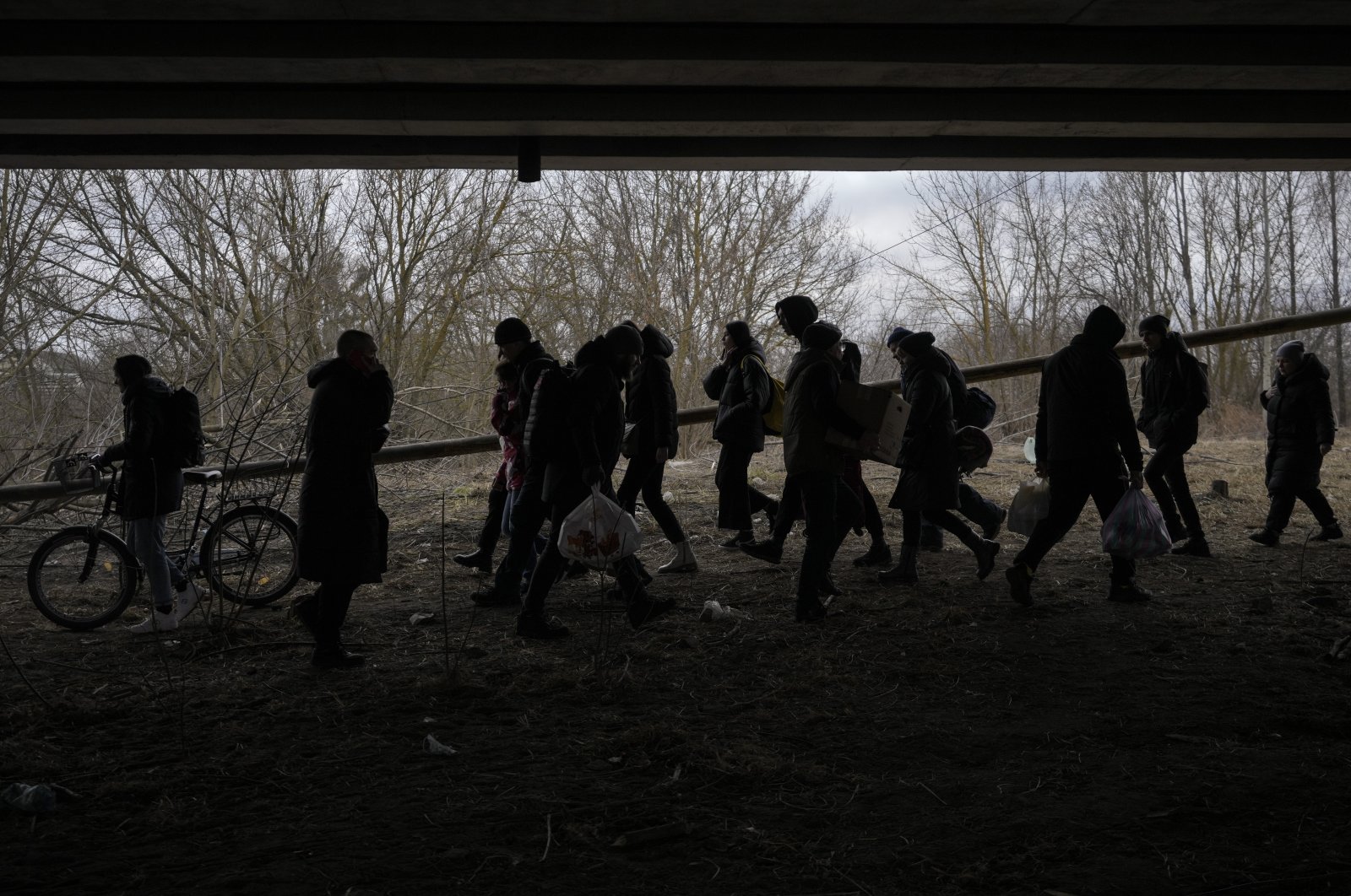 People walk along an improvised path under a bridge that was destroyed by a Russian airstrike, while fleeing the town of Irpin, Ukraine, March 5, 2022. (AP Photo)