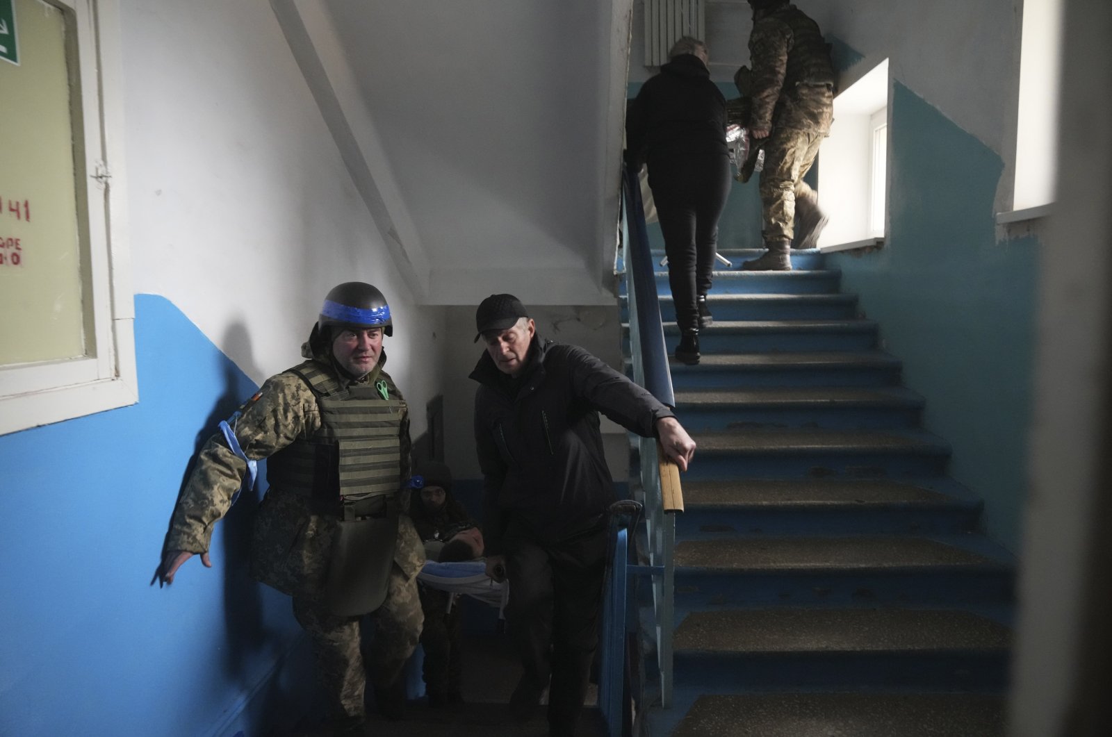 A Ukrainian soldier and a civilian carry a man who was injured by shelling in a hospital in Mariupol, Ukraine, March 3, 2022. (AP Photo)