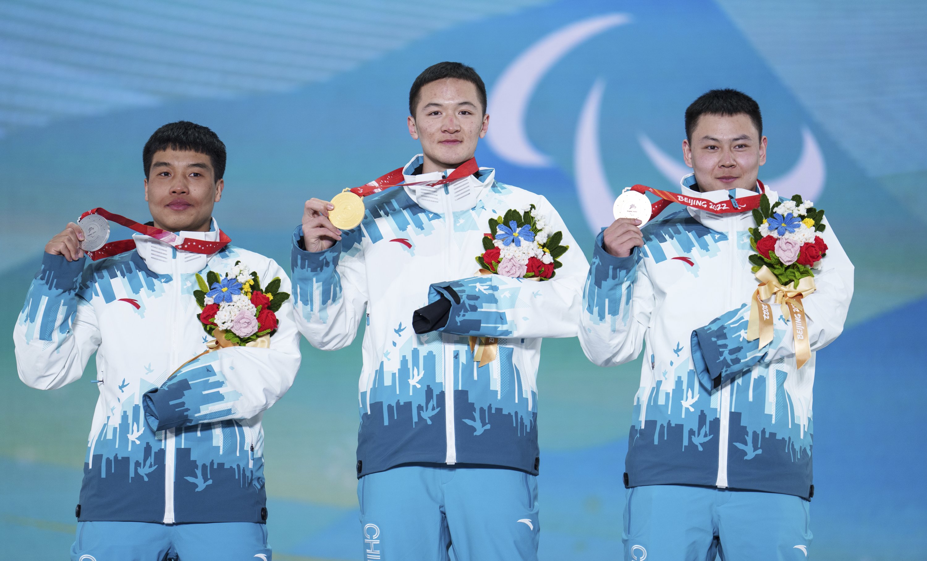 Peraih medali emas Lijia Ji (tengah) Peraih medali perak Pengyao Wang (kiri) dan peraih medali Perunggu Yonggang Zhu, semuanya dari Tiongkok, menunjukkan medali Paralimpiade Musim Dingin Beijing 2022 untuk para snowboard men's snowboard cross event, Zhangjiakou, Tiongkok, 7 Maret 2022. (AP Foto)