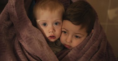 The children of medical workers warm themselves in a blanket as they wait for their relatives in a hospital in Mariupol, Ukraine, March 4, 2022. (AP Photo)