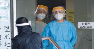 Health care workers wearing personal protective equipment stand at a clinic designated to treat coronavirus patients, in Hong Kong, China, March 7, 2022. (Reuters Photo)