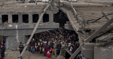 Ukrainians crowd under a destroyed bridge as they try to flee crossing the Irpin river in the outskirts of Kyiv, Ukraine, March 5, 2022. (AP Photo)