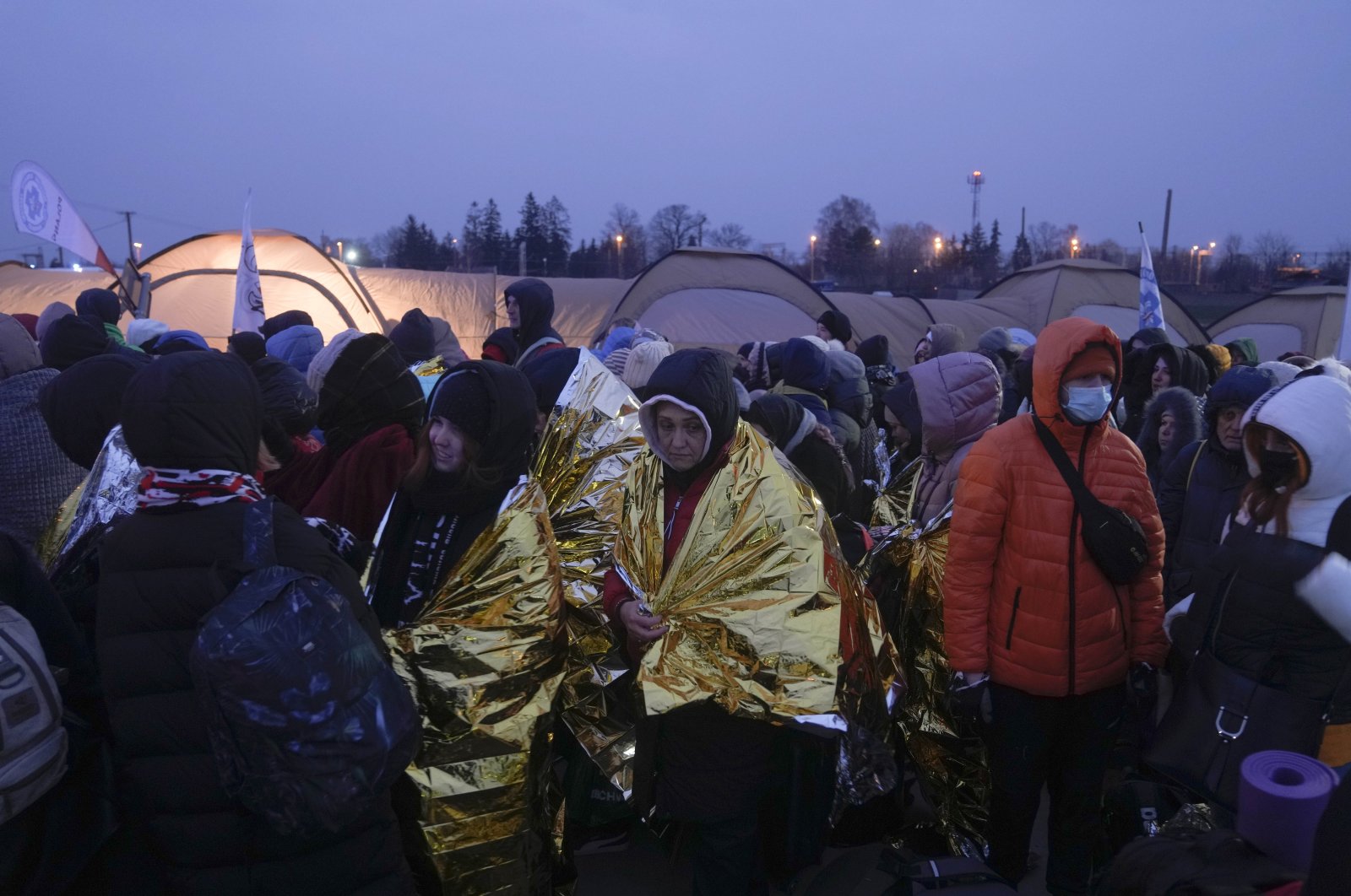 Refugees wait in a crowd for transportation after fleeing from Ukraine and arriving at the border crossing in Medyka, Poland, March 7, 2022. (AP Photo)