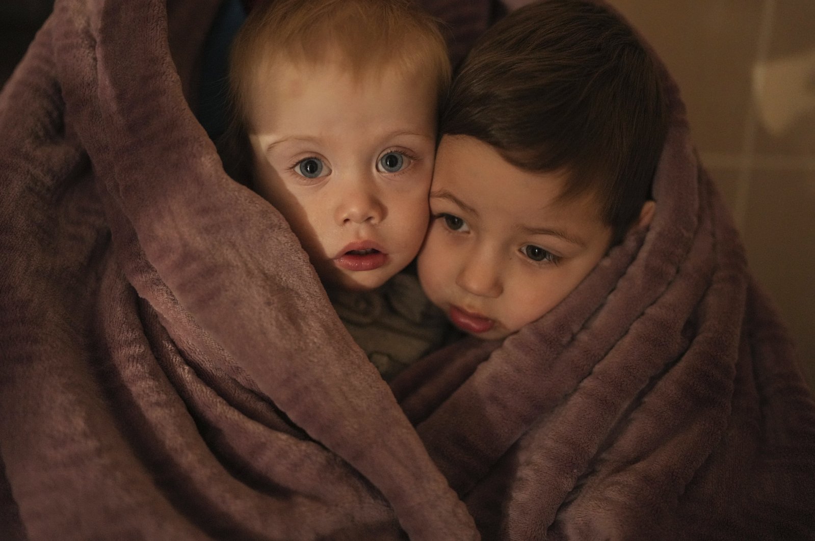 The children of medical workers warm themselves in a blanket as they wait for their relatives in a hospital in Mariupol, Ukraine, March 4, 2022. (AP Photo)