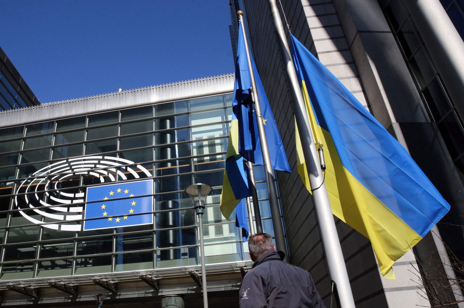 The Ukrainian flag is hoisted alongside the European Union flag outside the European Parliament headquarters to show their support for Ukrania after the nation was invaded on Feb. 24 by Russia, in Brussels, Belgium, Feb. 28, 2022. (AFP Photo)