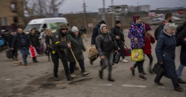 A Ukrainian police officer helps people as artillery echoes nearby while fleeing Irpin in the outskirts of Kyiv, Ukraine, March 7, 2022. (AP Photo)