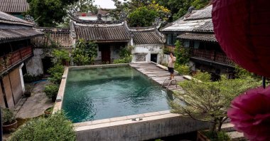 Poosak Posayachinda, the owner of the So Heng Tai mansion, takes a phone call by the swimming pool, Bangkok, Thailand. Feb. 15, 2022. (AFP Photo)