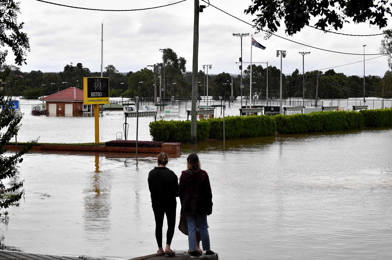 Residents look at the rising floodwaters near the commercial area in the southwestern Camden suburb of Sydney, March 8, 2022. (AFP Photo)