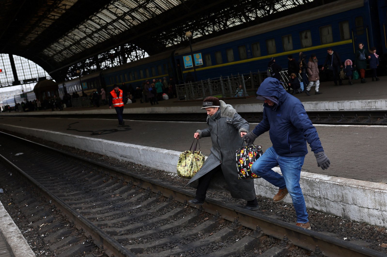 Refugees fleeing the ongoing Russian invasion of Ukraine cross the tracks after arriving on a train from Kyiv region at the train station in Lviv, Ukraine, March 8, 2022. (Reuters Photo)