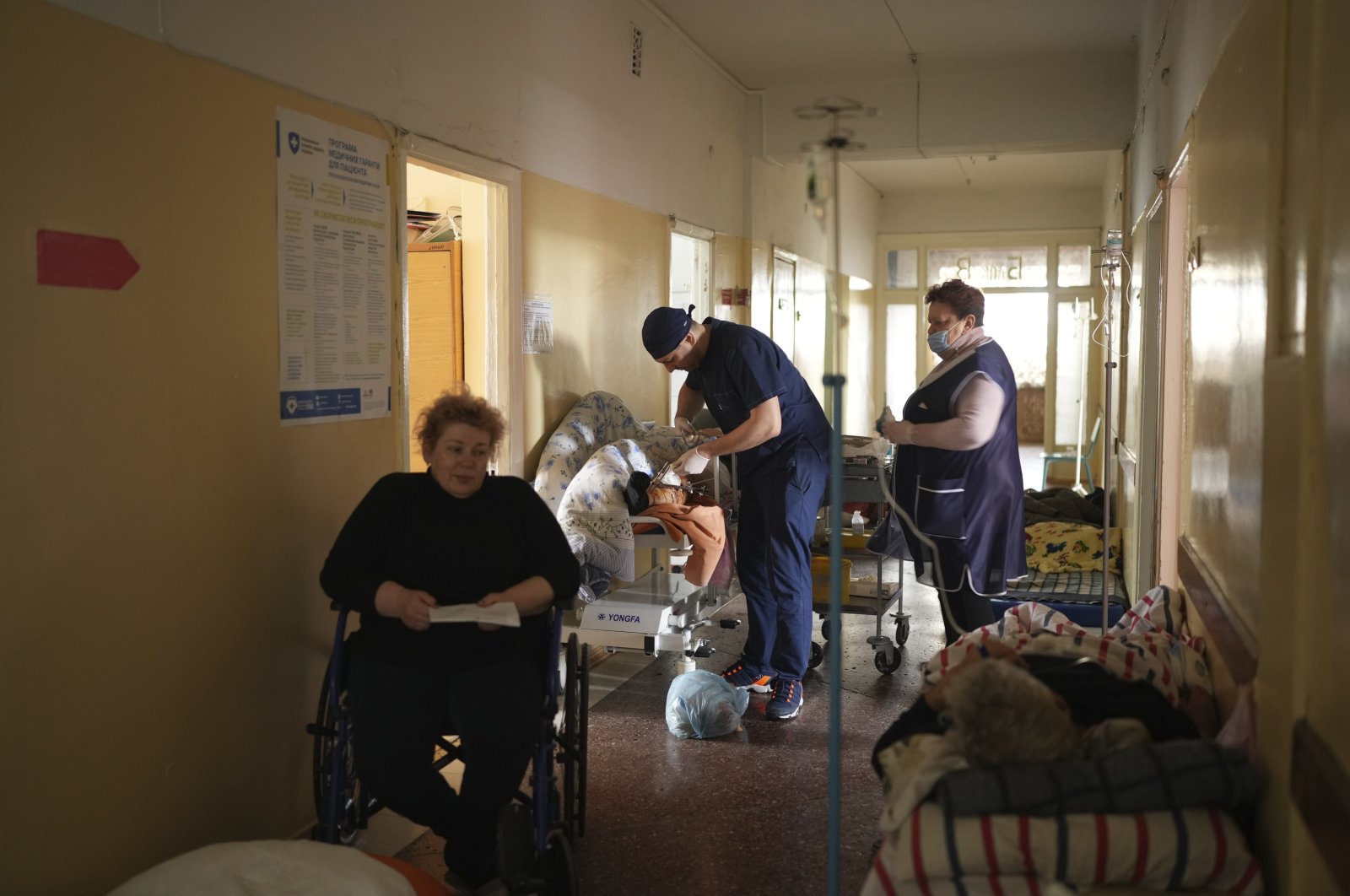 A medical worker (C) treats a man wounded by shelling in a hospital in Mariupol, Ukraine, March 4, 2022. (AP Photo)