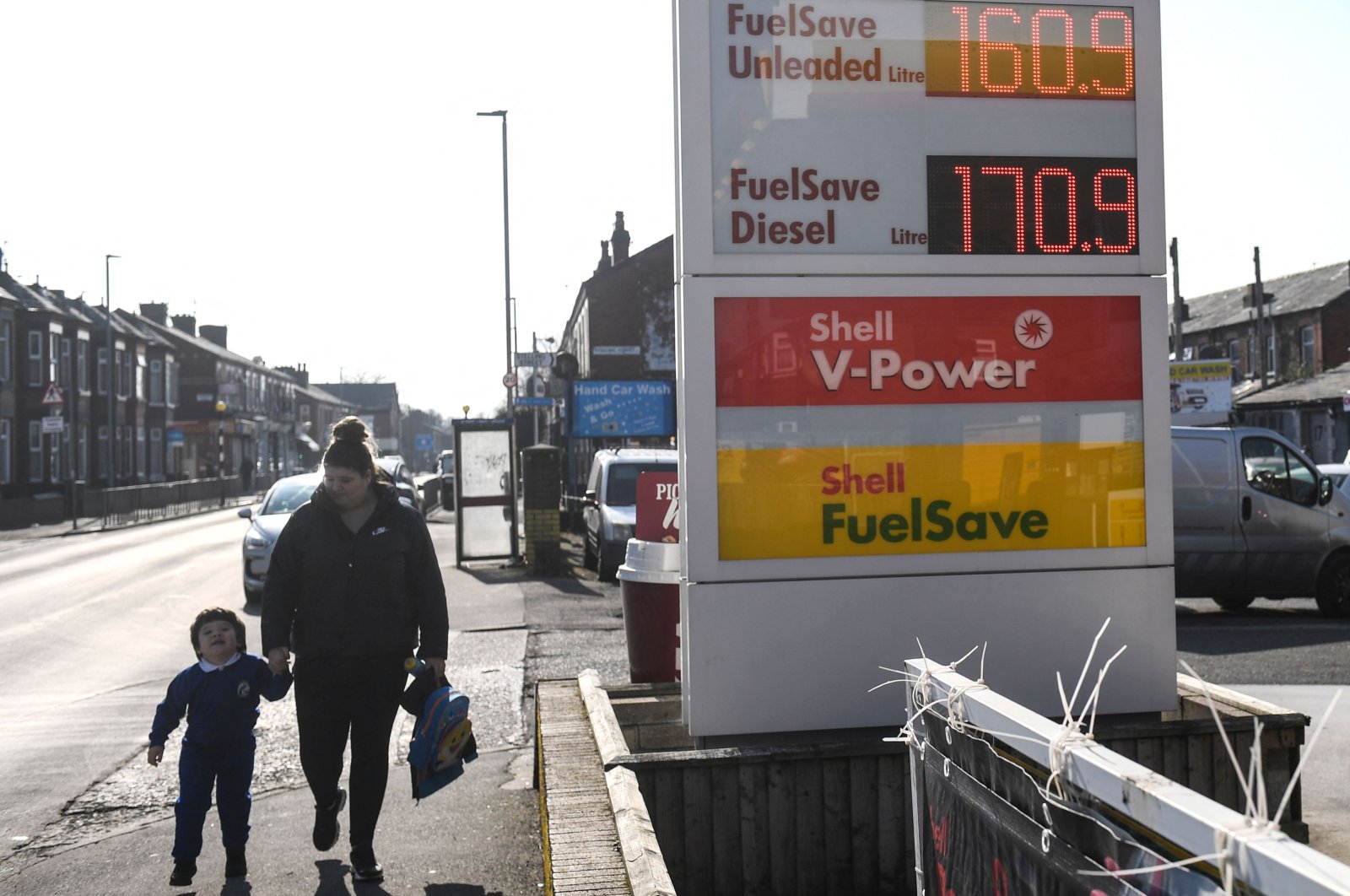 People walk past a board indicating the prices of petrol and diesel fuel at a Shell petrol station, in Manchester, U.K., March 8, 2022. (AFP Photo)