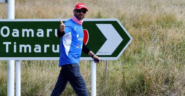 Temel Ataçocuğu waves as he walks toward Christchurch, near Katiki, North Otago, New Zealand, March 4, 2022. (AFP Photo)