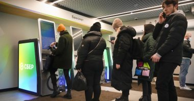 People stand in line to withdraw money from an ATM in Sberbank in St. Petersburg, Russia, Feb. 25, 2022. (AP Photo)
