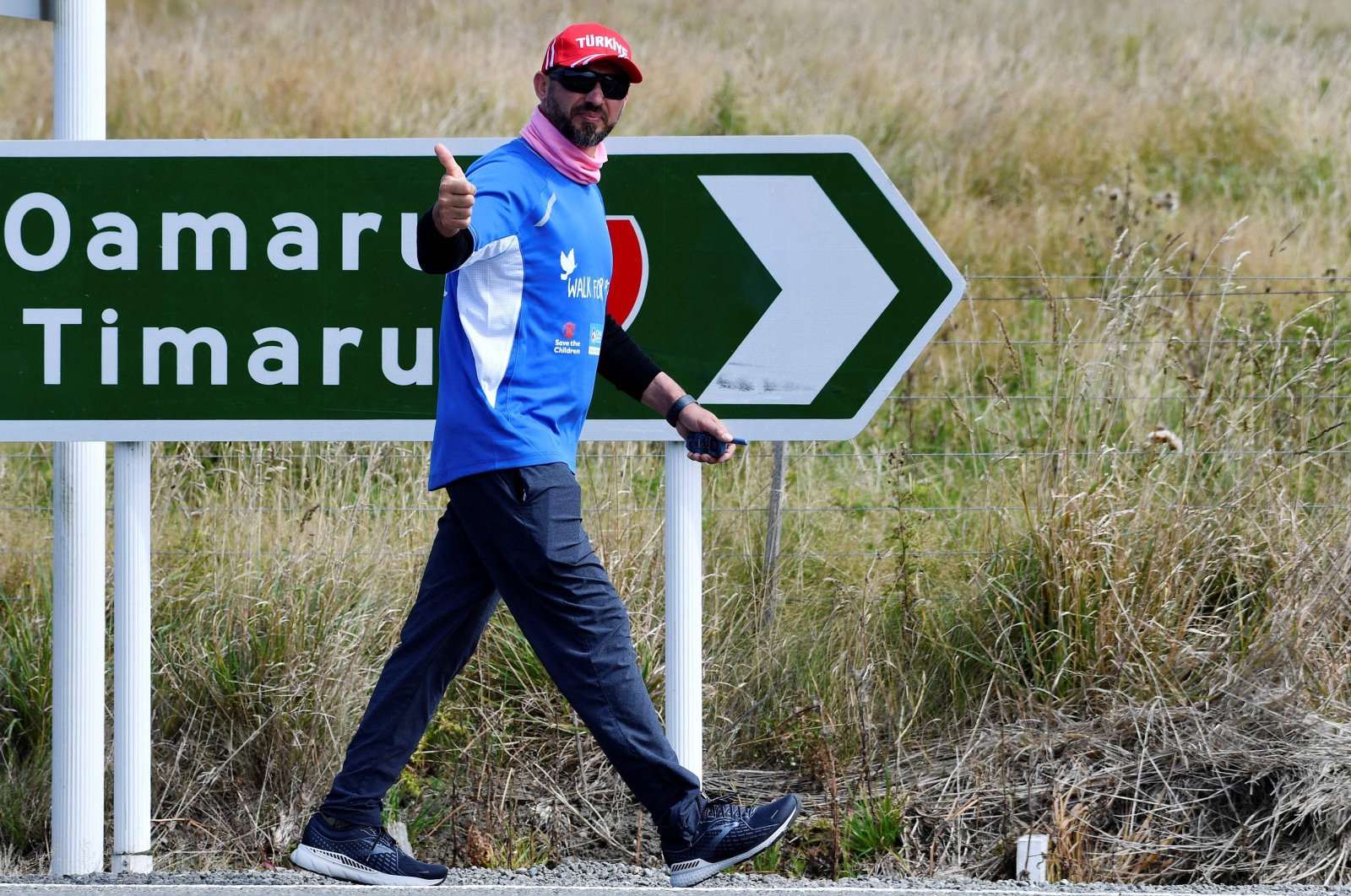 Temel Ataçocuğu waves as he walks toward Christchurch, near Katiki, North Otago, New Zealand, March 4, 2022. (AFP Photo)