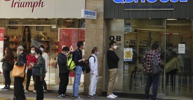 People wearing face masks queue up to get a haircut at a salon after reopening in Hong Kong, March 10, 2022. (AP Photo)