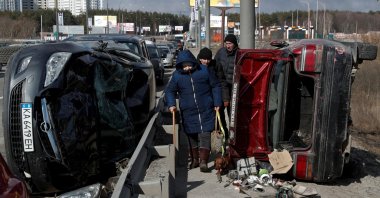 People walk between destroyed cars as they evacuate from Irpin, as Russia's attack on Ukraine continues, outside of Kyiv, Ukraine March 10, 2022. (Reuters Photo)
