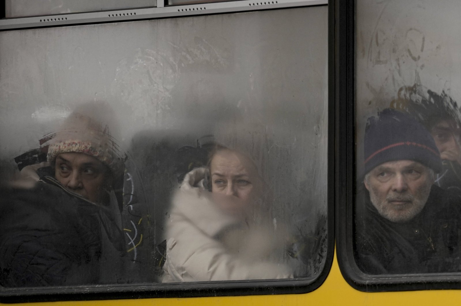 People look out a steamy bus window with drawings on it as civilians are evacuated from Irpin, on the outskirts of Kyiv, Ukraine, March 9, 2022. (AP Photo)