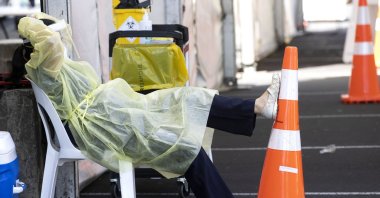 A health worker rests at the Waipareira Trust drive-in COVID-19 testing station in Auckland, New Zealand, March 8, 2022. (AP Photo)