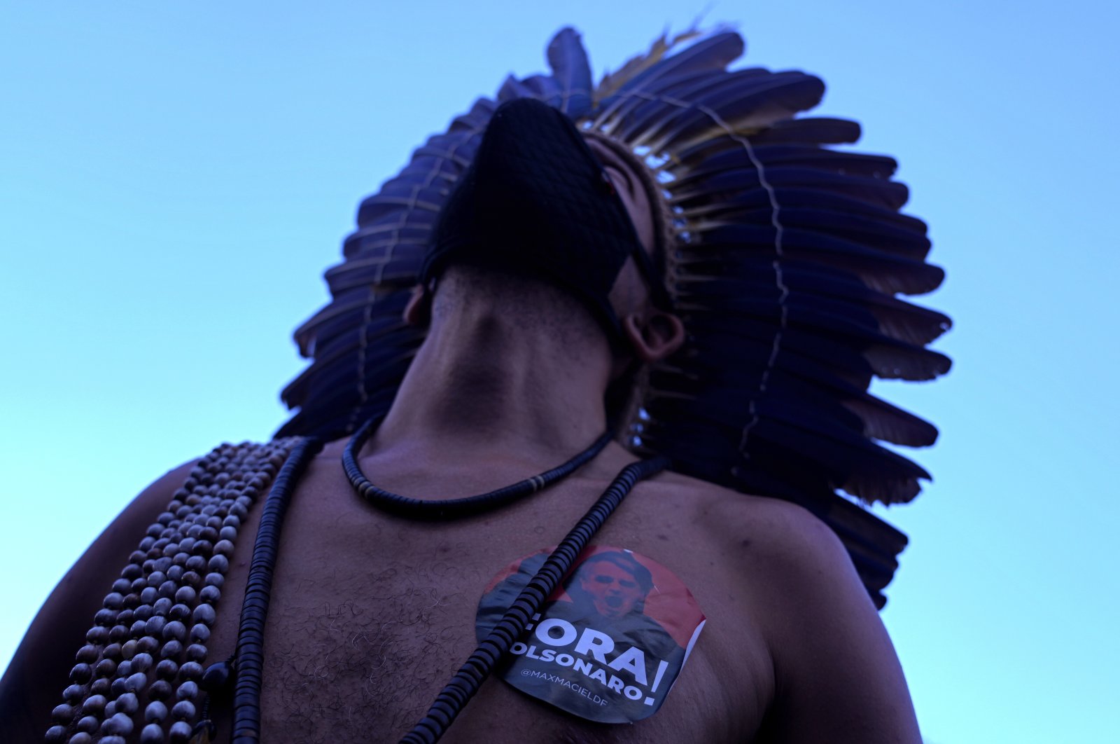 An indigenous Pataxo man with a sticker on his chest that reads in Portuguese &quot;Out Bolsonaro,&quot; participates in a demonstration by the &quot;Act for the Earth&quot; movement in front of the National Congress in Brasilia, Brazil, March 9, 2022. (AP Photo)