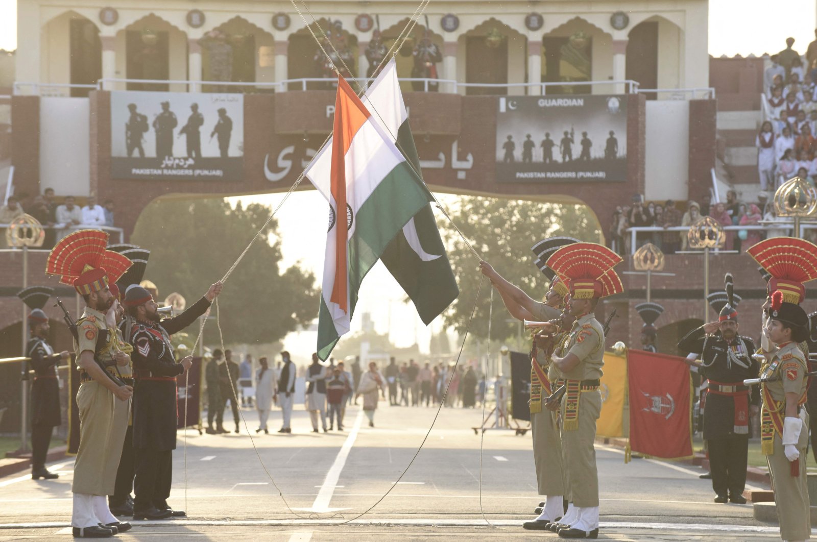 Indian Border Security Force personnel (in brown uniforms) and Pakistani Rangers (in black uniforms) take part in the beating retreat ceremony at the India-Pakistan Wagah border post, March 9, 2022. (AFP Photo)