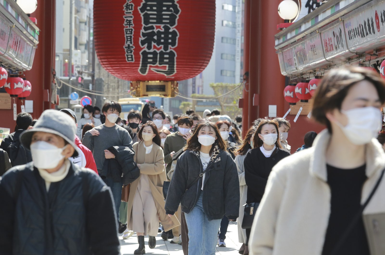 People wearing face masks to protect against the spread of the coronavirus walk through a shopping arcade in the Asakusa district in Tokyo, Japan, March 7, 2022. (AP Photo)