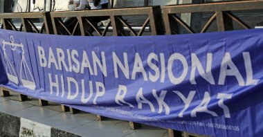 Nur Fadzlina Dahlan, 23, (L) and Nur Izzati Fitrah, 23, stand at a bus stop decorated with a Barisan Nasional banner, during the campaign period of the Johor state election at Johor Baru, Johor, Malaysia on March 4, 2022. (Reuters Photo)