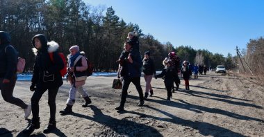 People walk along a road by a forest, as they flee Russia's invasion of Ukraine, in the Vyshgorod region near Kyiv, Ukraine, March 10, 2022.  (Reuters Photo)