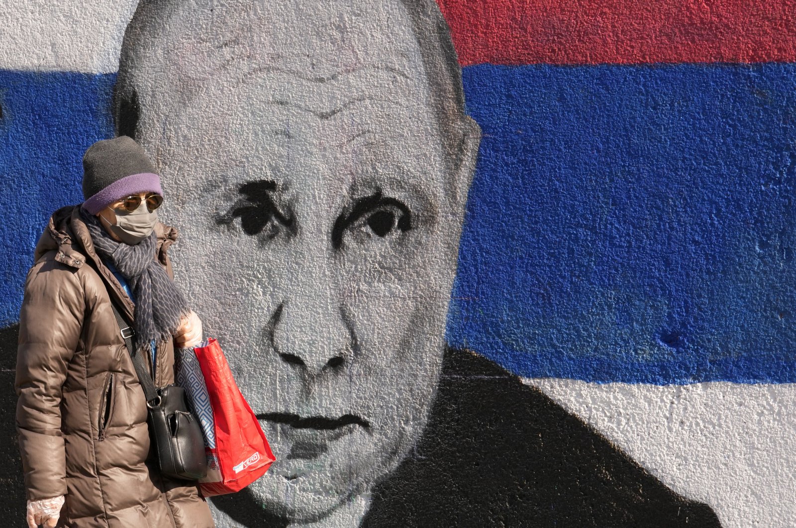 A woman passes by a mural depicting the Russian President Vladimir Putin in Belgrade, Serbia, March 12, 2022. (AP Photo)