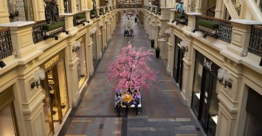 Three women eat ice cream as a small number of visitors walk inside the GUM department store in Moscow, Russia, March 9, 2022. (AP Photo)