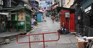 A man looks at his phone on an empty street in Hong Kong on March 13, 2022. (AFP Photo)