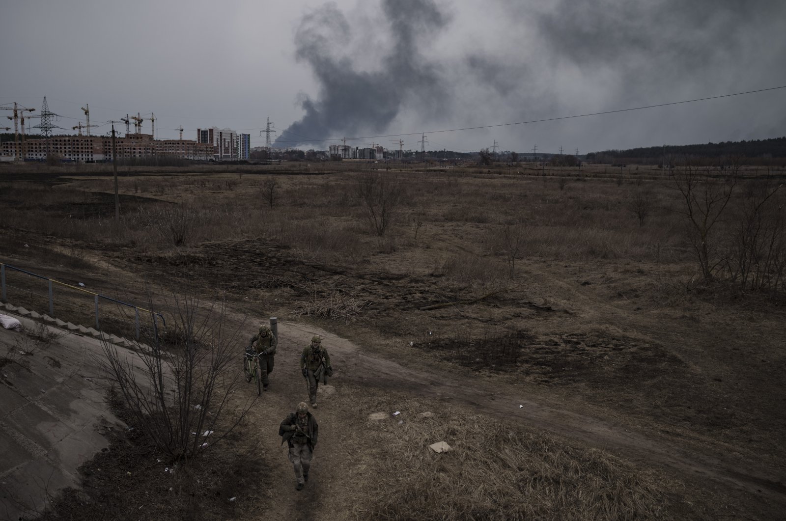 Soldiers walk on a path as smoke billows from the town of Irpin, on the outskirts of Kyiv, Ukraine, March 12, 2022. (AP Photo)